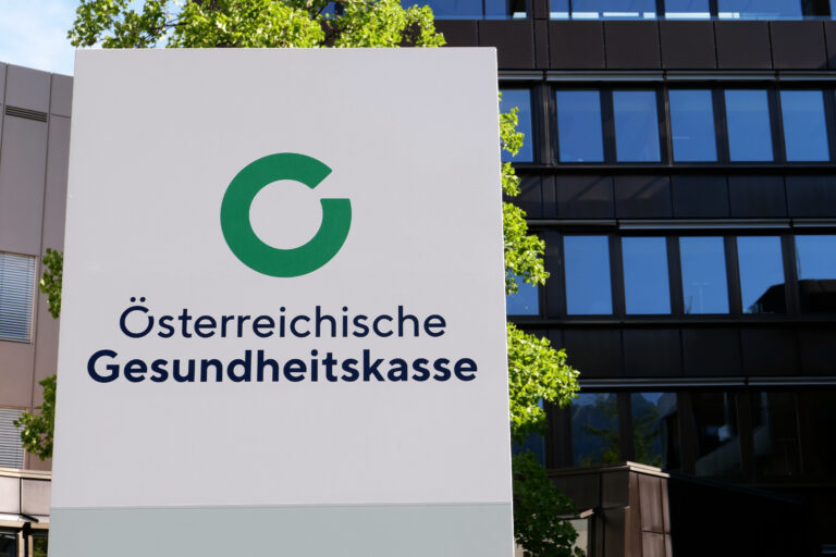 Symbolbild: Logo der Österreichischen Gesundheitskasse (ÖGK vor einem Bürogebäude.