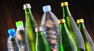 Ein Gruppe unterschiedlichster Flaschen steht eng zusammen. einige sind durchsichtig, einige grün gefärbt, manche aus Glas, andere aus Plastik.