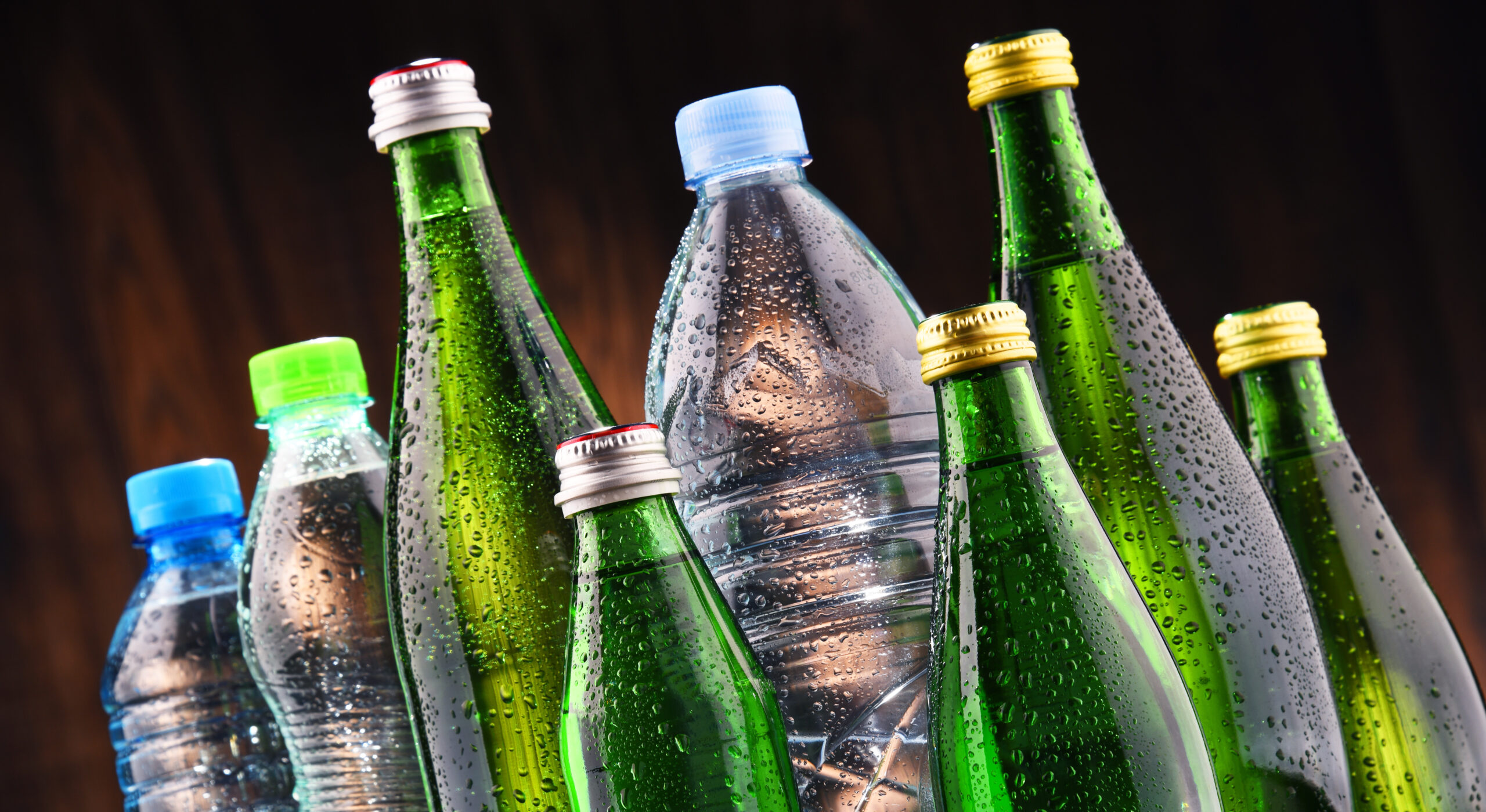 Ein Gruppe unterschiedlichster Flaschen steht eng zusammen. einige sind durchsichtig, einige grün gefärbt, manche aus Glas, andere aus Plastik.