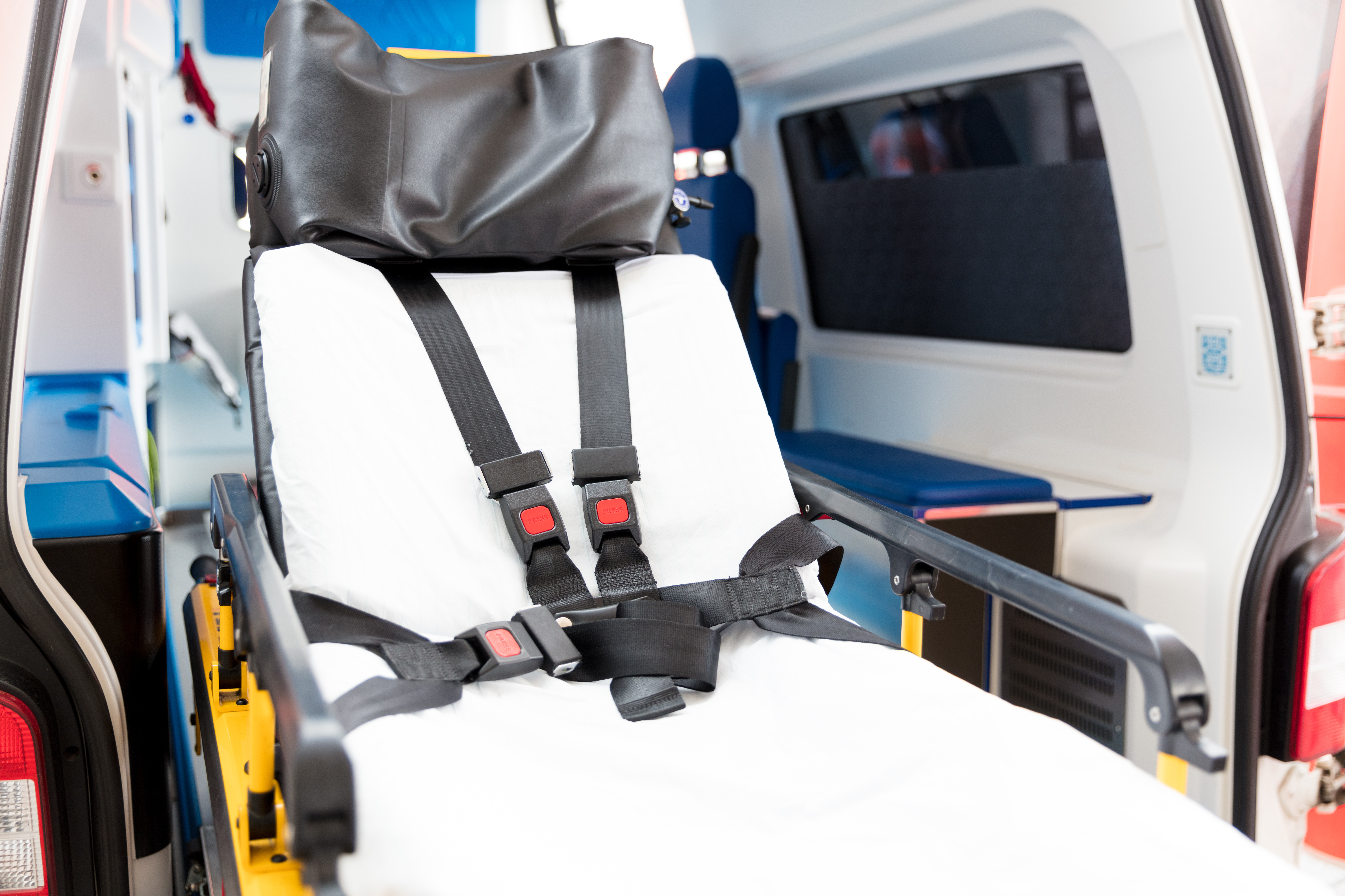 Leere Krankenliege mit mehreren Gurten im Inneren eines Rettungswagens.
