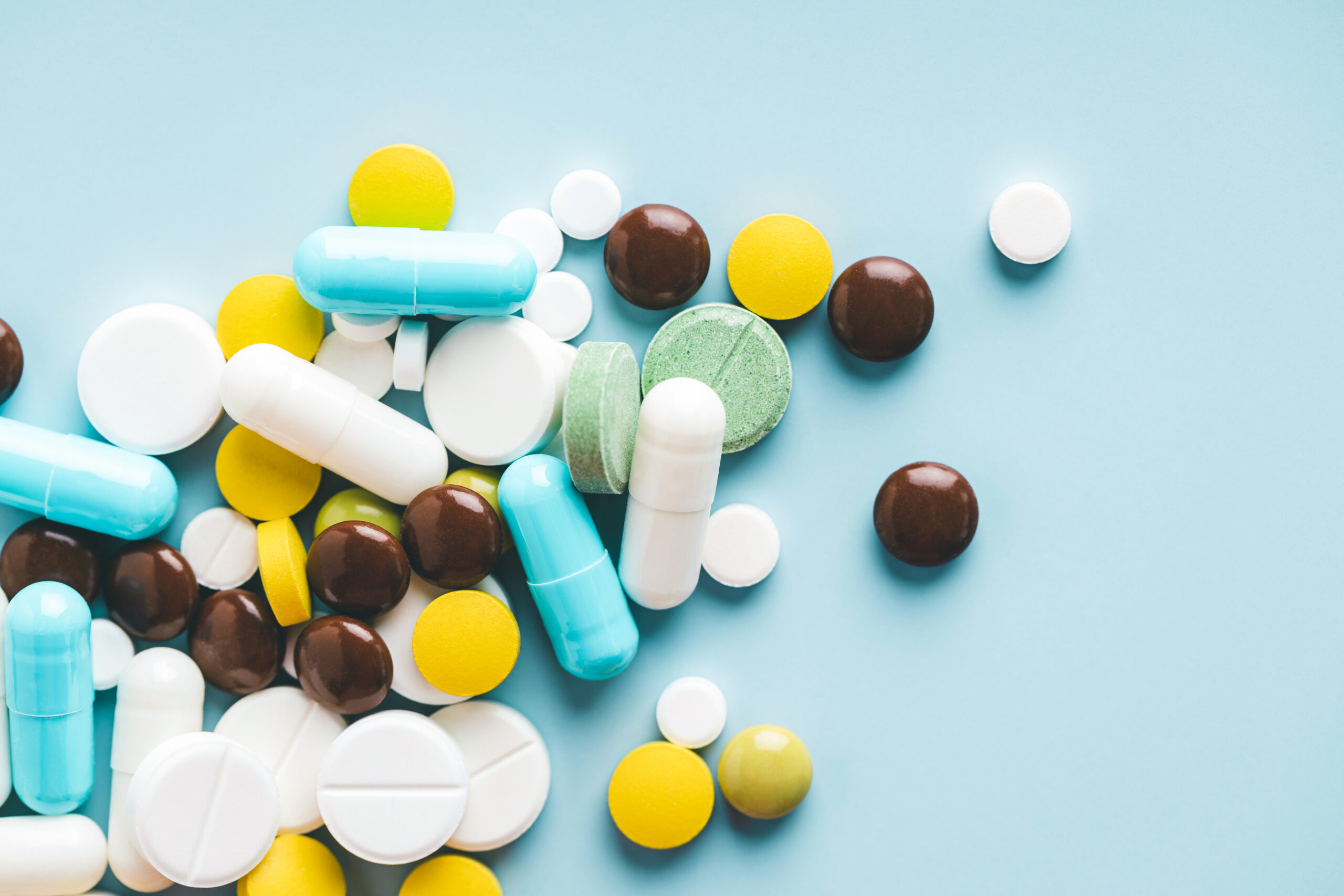 Verschiedene Tabletten und Kapseln in unterschiedlichen Farben stellen die Vielfalt an Arzneimitteln dar.