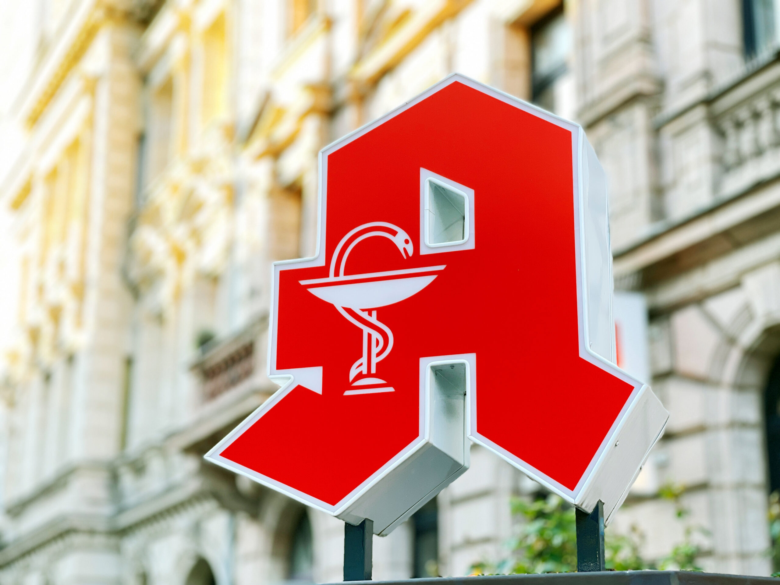 Deutsches Apotheken-Logo hängt an einer Hauswand.