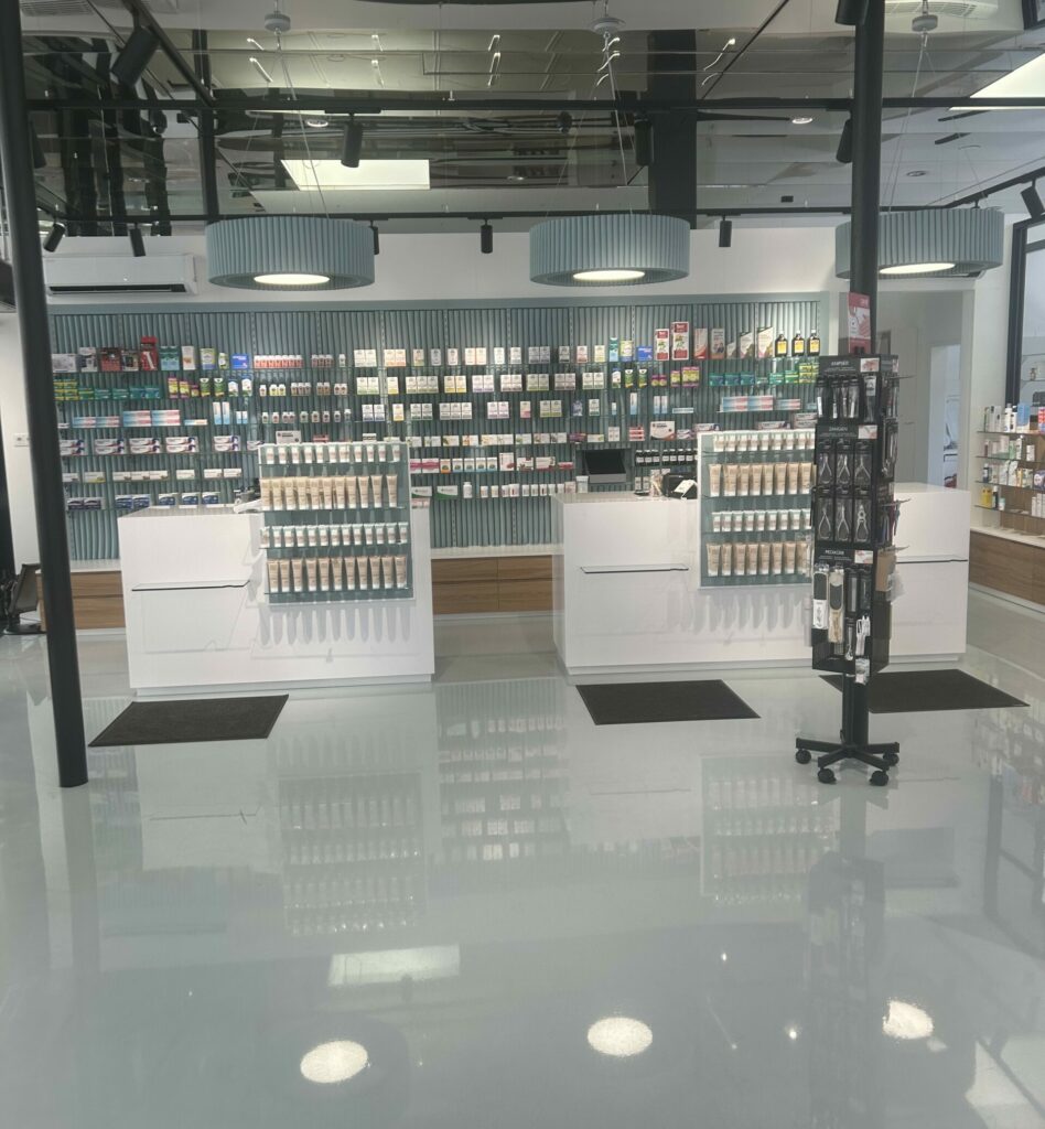 Das Design der Apotheke wird gezeigt. Verspiegelte Decken und der glänzende Boden in den Leitfarben graublau.