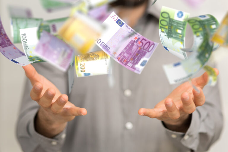 Geldscheine fallen von der Decke und Mann streckt seine Hände danach aus.