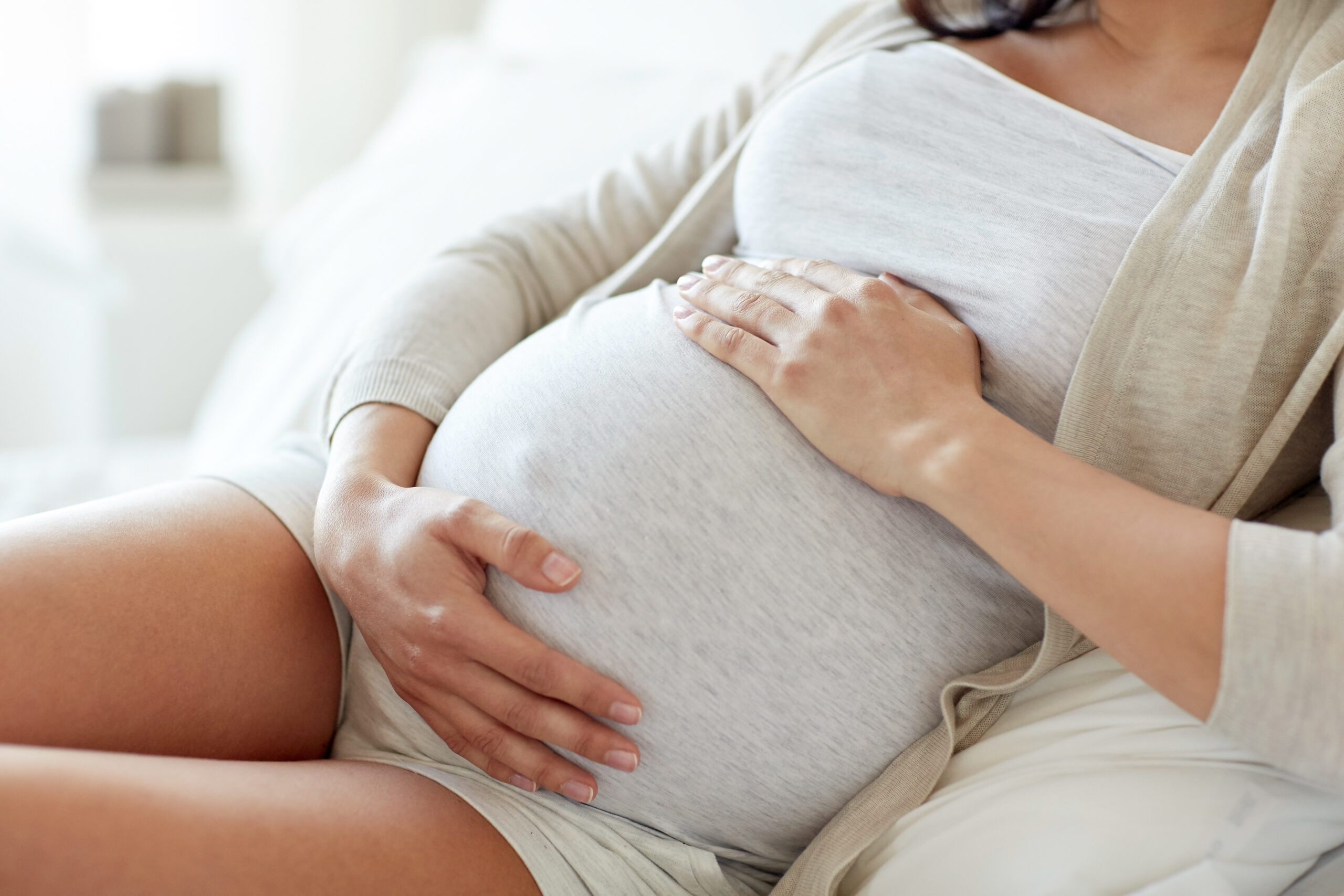Frau streichelt ihren Schwangerschaftsbauch.