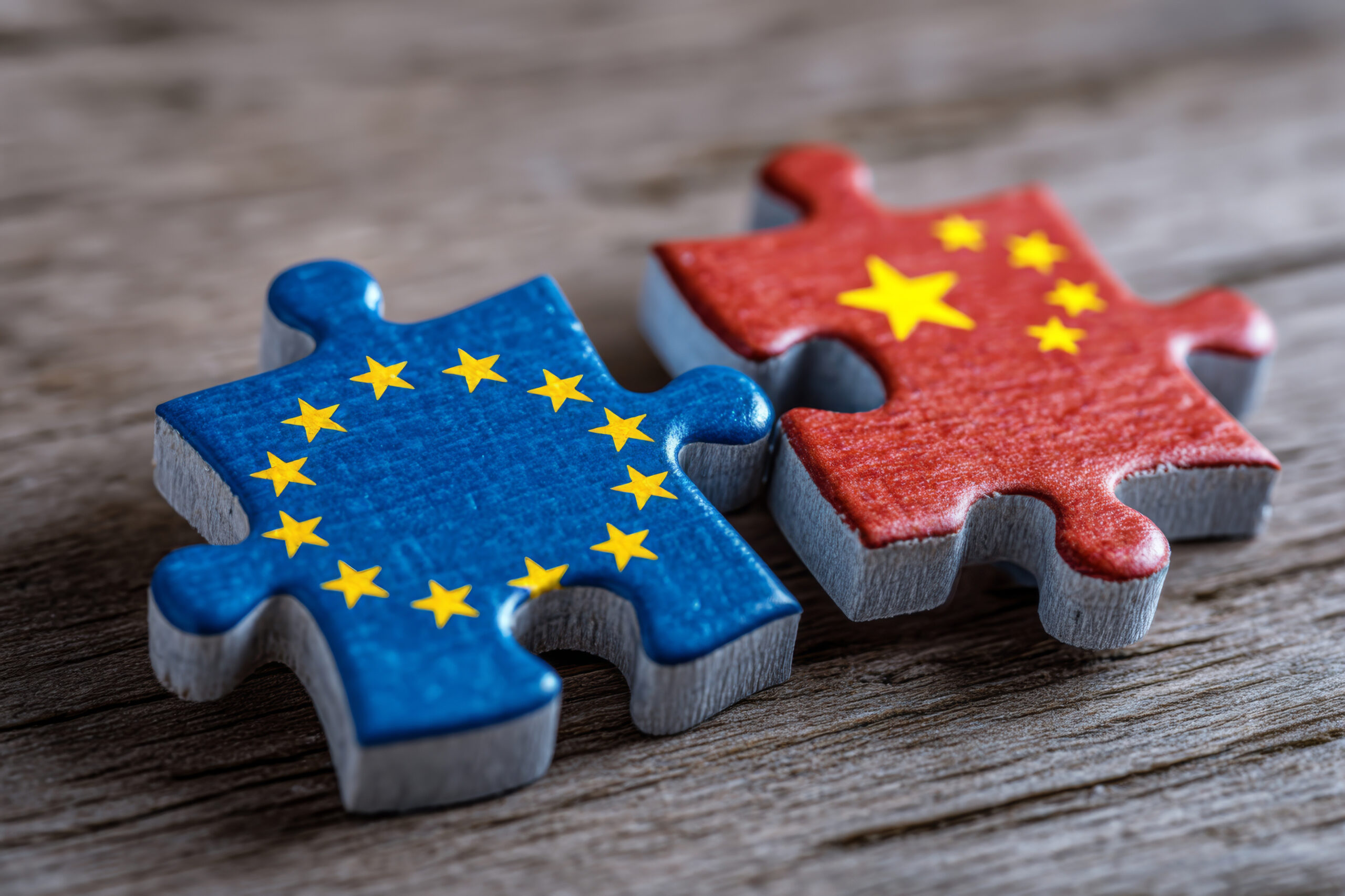 Zwei Puzzleteile liegen nebeneinander. Auf einem ist die EU-Fahne aufgedruckt, am anderen die von China.