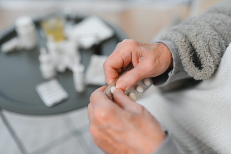 Alte Person drückt Tabletten aus einem Blister.