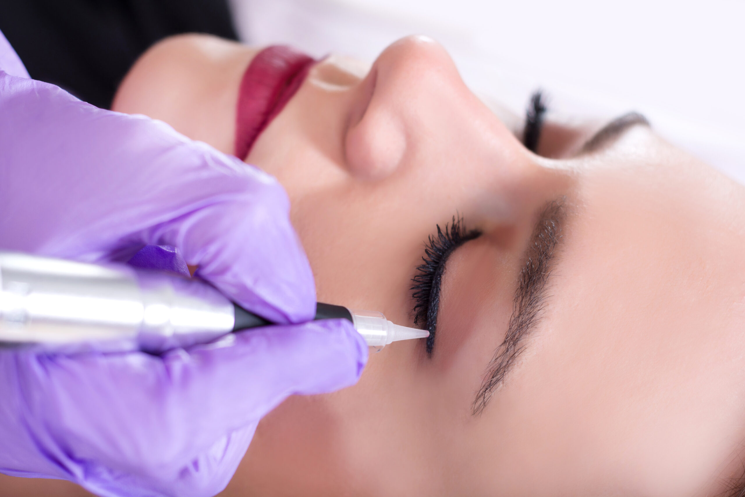 Frau wird am Wimpernrand tätowiert.