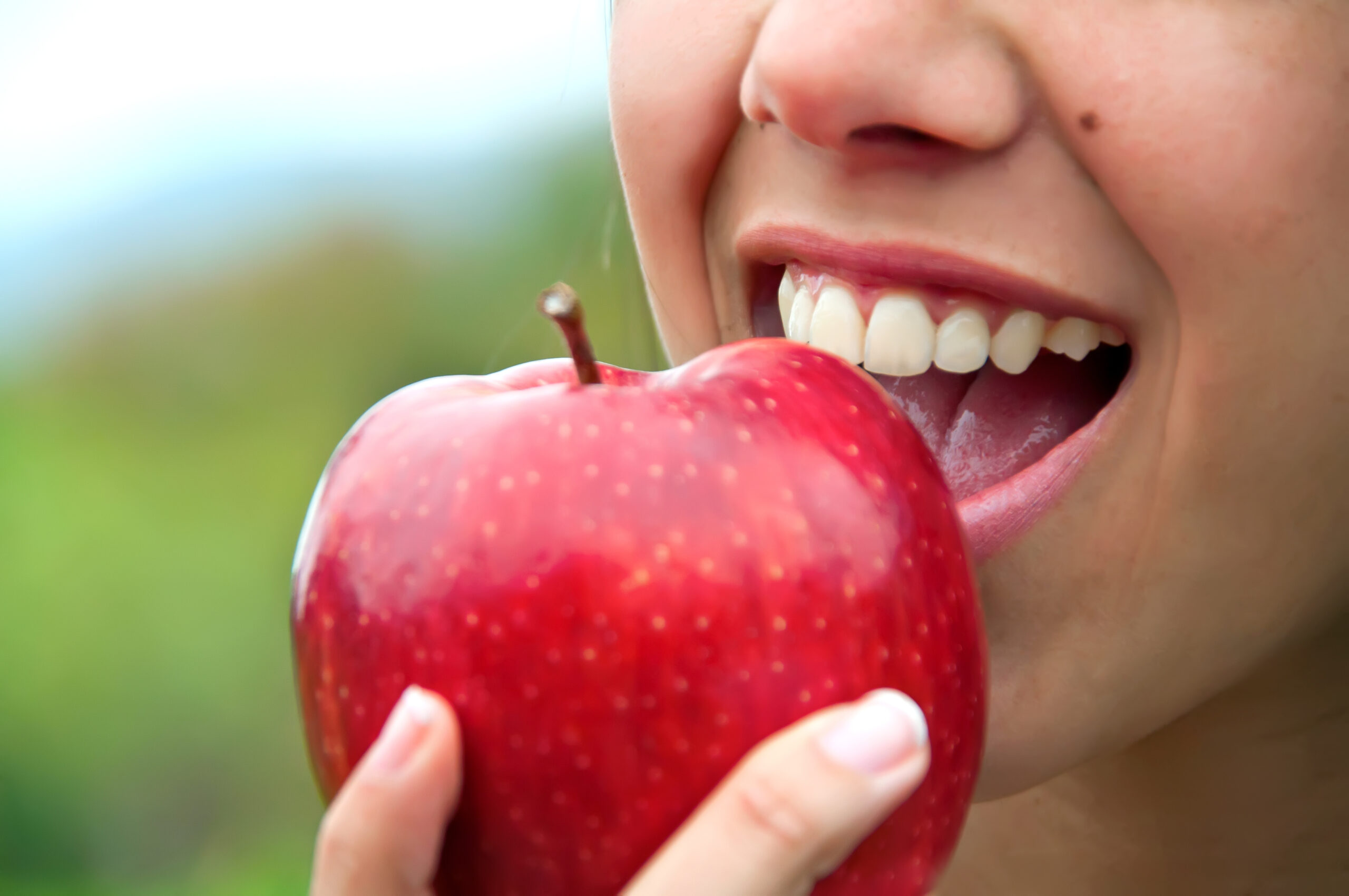 Frau beißt in roten Apfel.