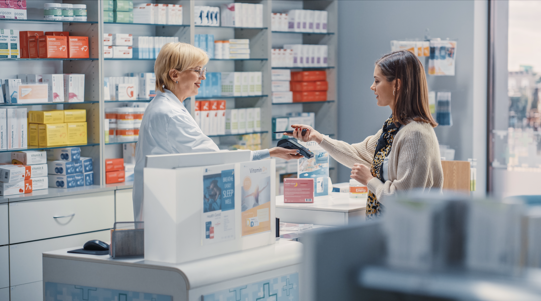 Kundin zahlt in einer Apotheke bei der Apothekerin mit Bankomatkarte.