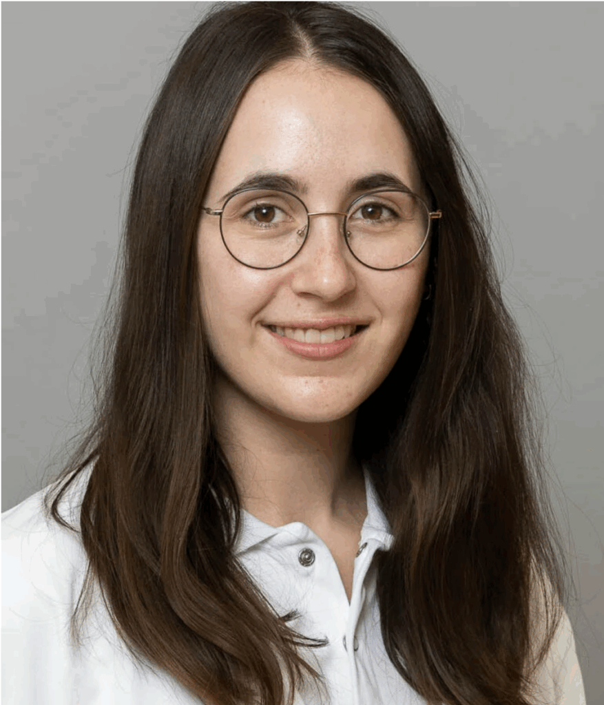 Nina trägt Brille, lange Haare und lächelt in die Kamera.