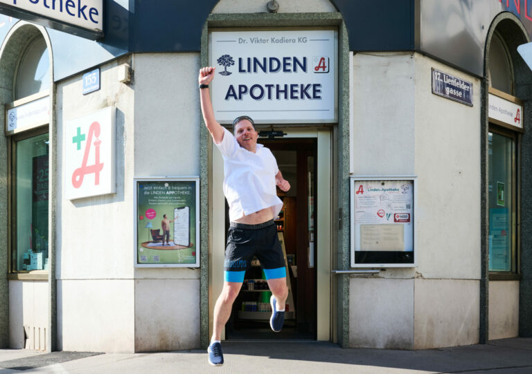 Mann springt vor der Apotheke und streckt eine Faust in die Höhe.