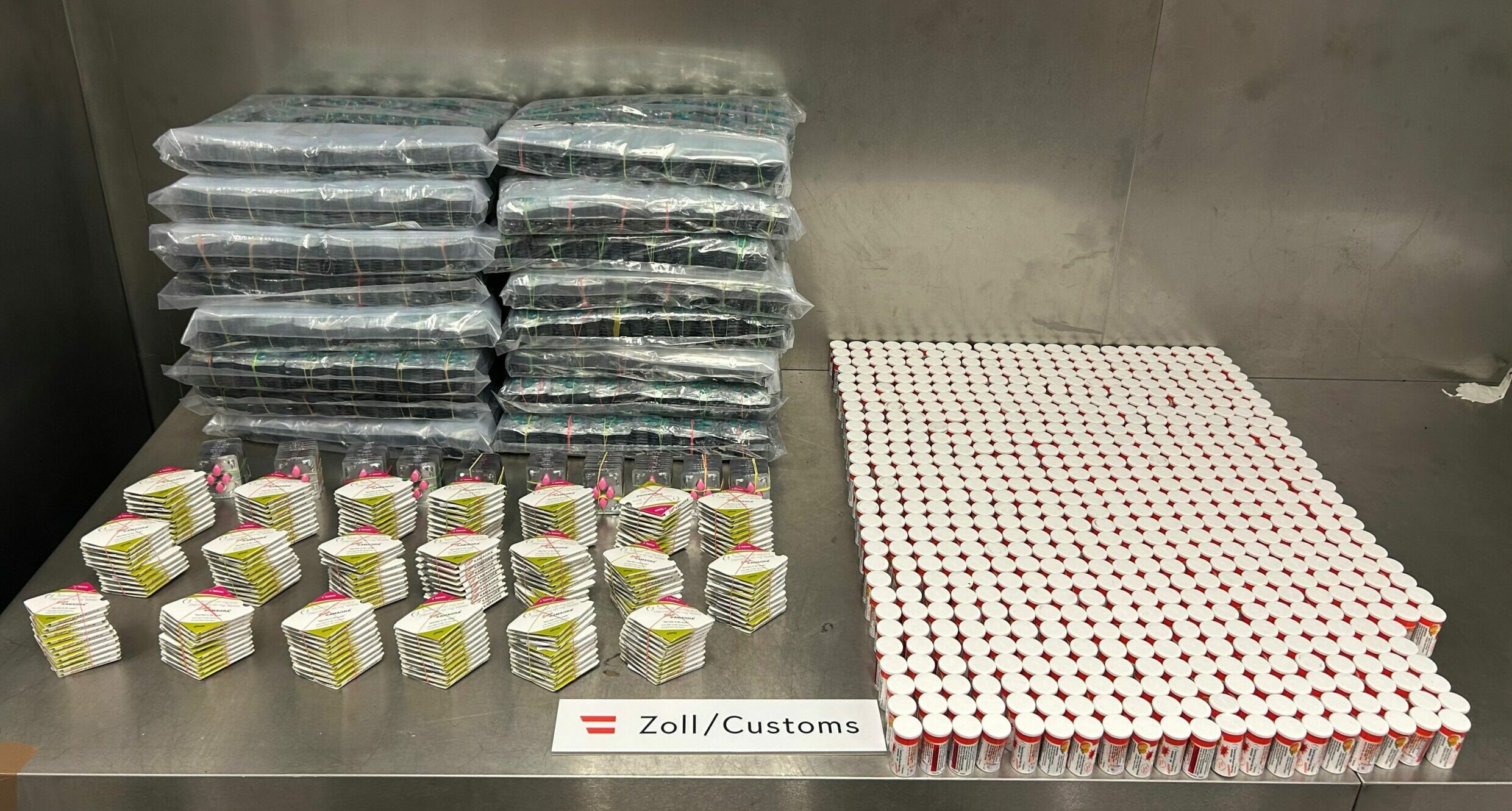 Auf einer Ablage sind die geschmuggelten Pillen zu sehen. Fein säuberlich aufgereiht. Vorne in Papierumschlägen, rechts in Dosen und hinten links in Plastik verpackt.