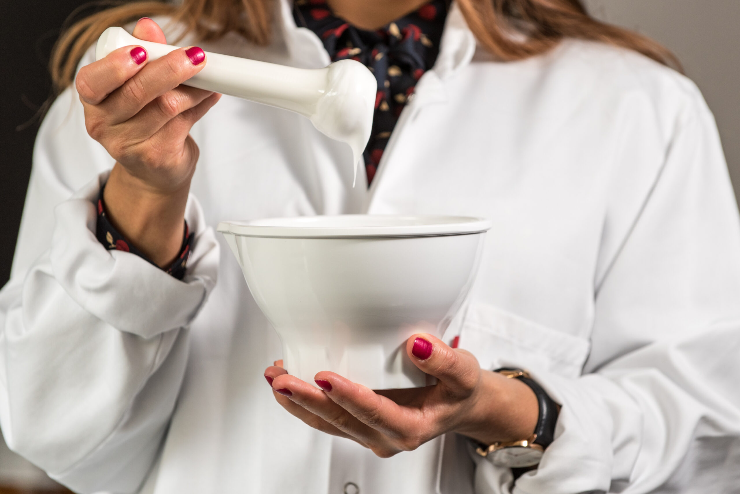 Apothekerin Pharmazeutisch-technische Assistentin stellt Rezeptur in Rührschale her und überprüft Creme am Pistill. Arbeitsplatz Apotheke