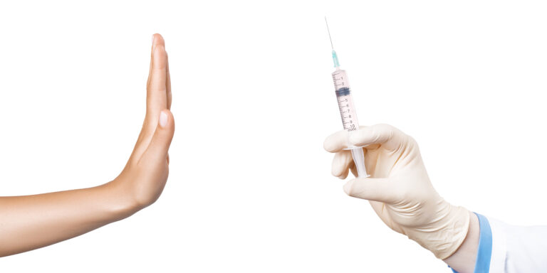 Eine Hand hält eine Spritze, eine andere deutet Stop.