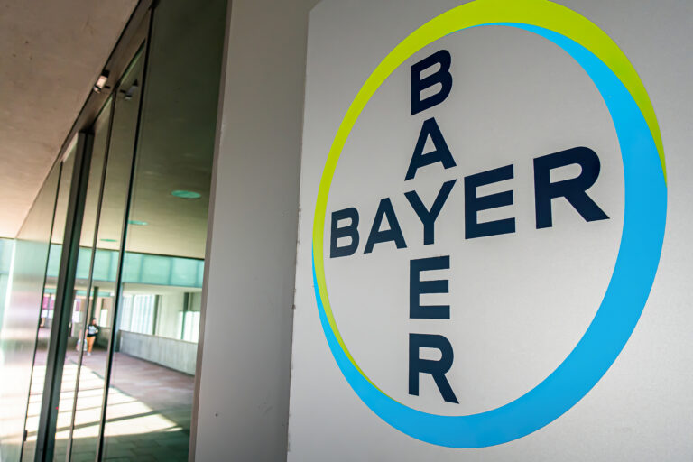 Das Bayer Logo ist auf einer Hausmauer zu sehen. Es ist blau und grün.