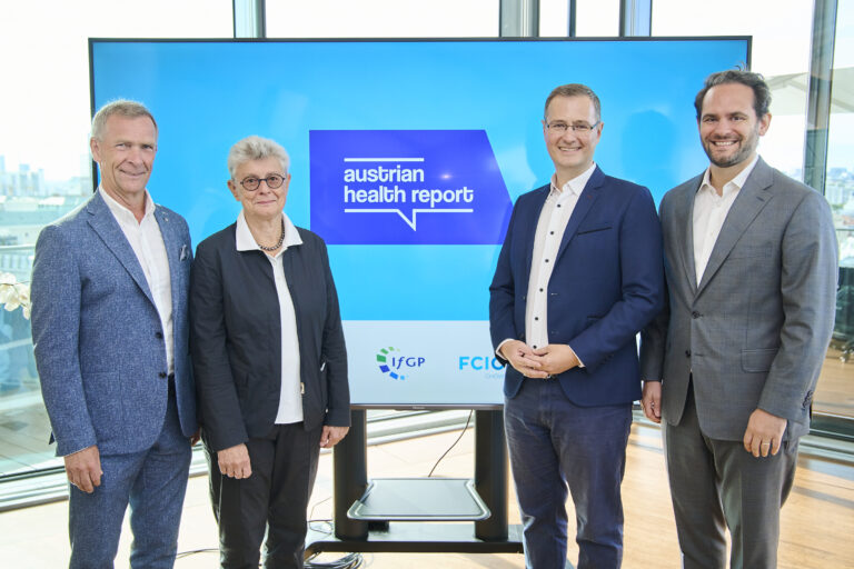 Bei der Pressekonferenz des Austrian Health Reports wurde ein Foto gemacht. Auf ihm sind die Vortragenden bzw. Beteiligten zu sehen. (v.l.n.r. Dr. Reinhard Raml, Dr. Ulrike Holzgrabe, Dr. Walter Feichtinger, Marco Pucci). Sie stehen vor einem Bildschirm.