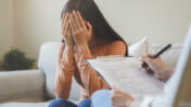 Symbolbild: Eine junge Frau hält sich die Arme vor das Gesicht. Sie ist in einer Therapiesitzung.