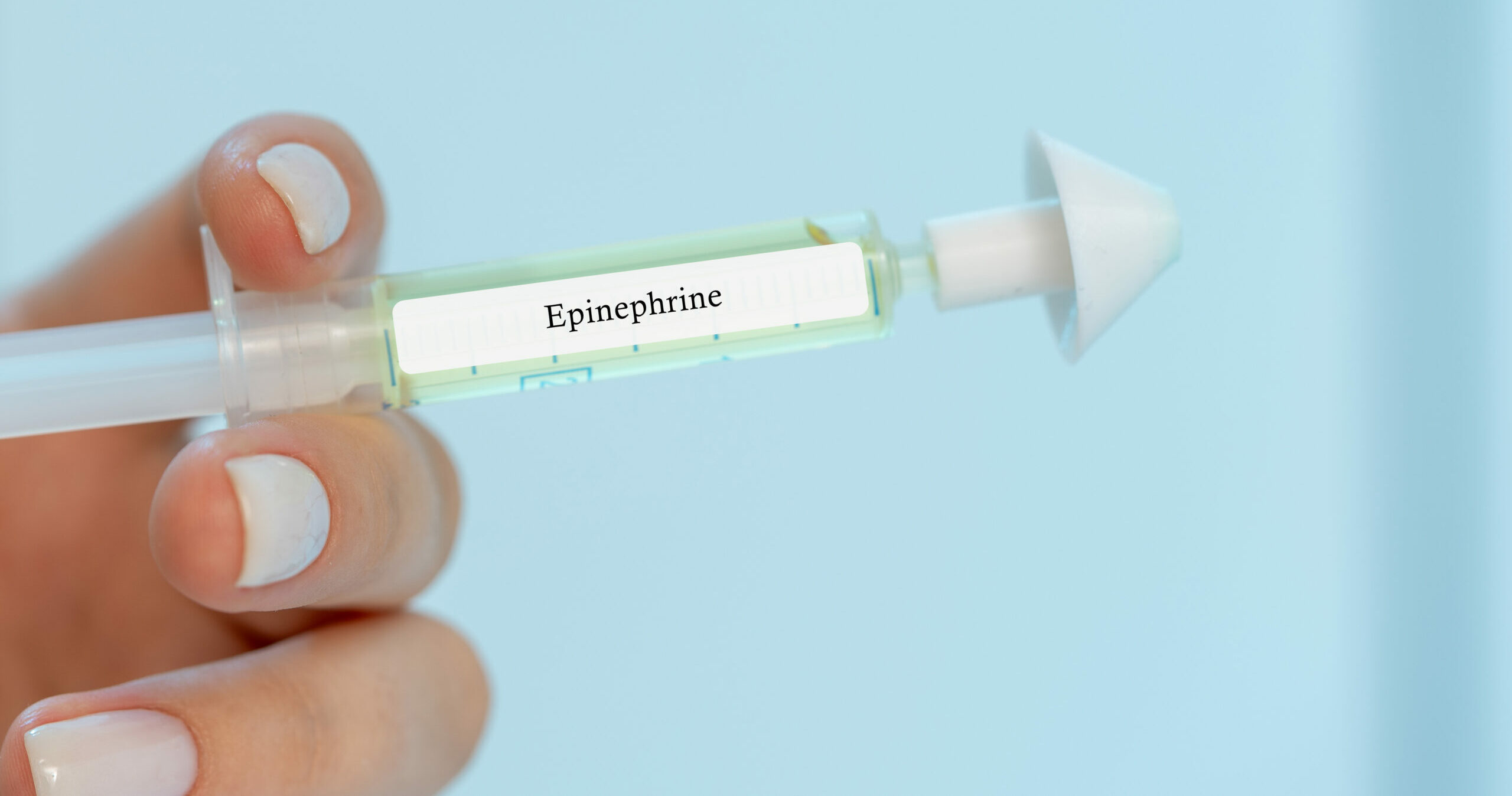 Symbolbild: Eine Hand mit weiß lackierten Nägel hält eine Nasale Spritze mit der Aufschrift "Epinephrine".