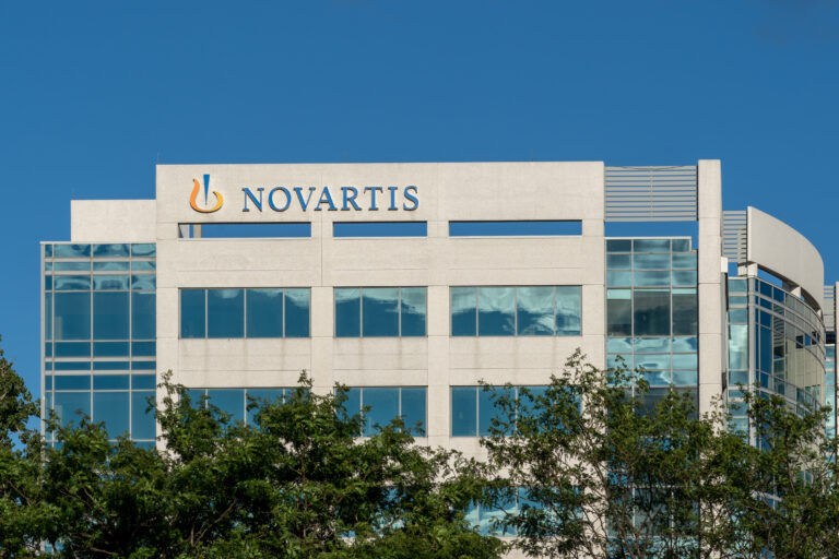 Symbolbild: Das Novartis Gebäude von außen. Ein groér Schriftzug ziert das Gebäude. Davor stehen Bäume.