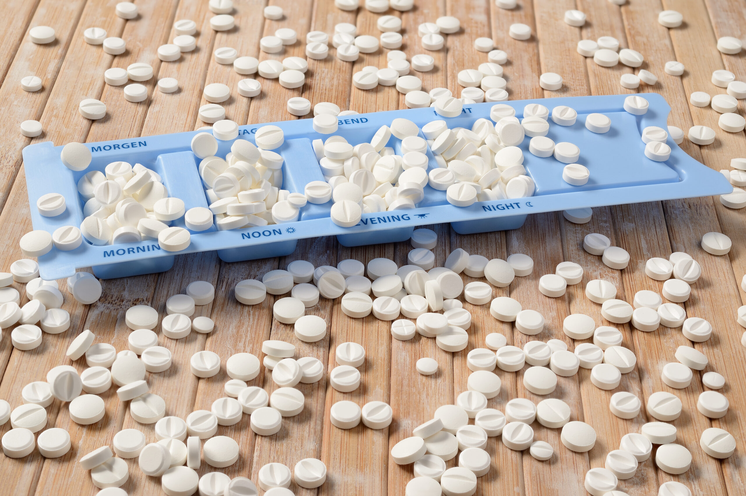 Symbolbild: Eine Einschachtel-Hilfe in blauem Plastik ist von weißen Tabletten nur so überdeckt. Eine große Menge liegt verstreut herum.