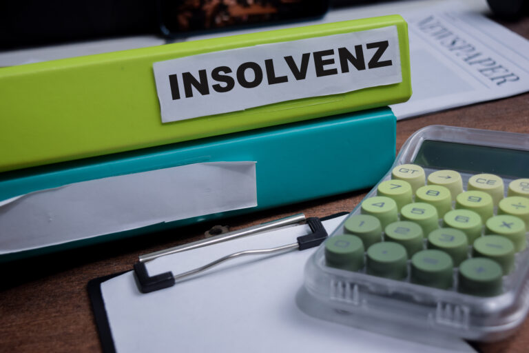 Symbolbild: Auf einem Tisch Ligen zwei Aktenordner. Auf einem Steht "Insolvenz", daneben liegt ein grüner Taschenrechner.