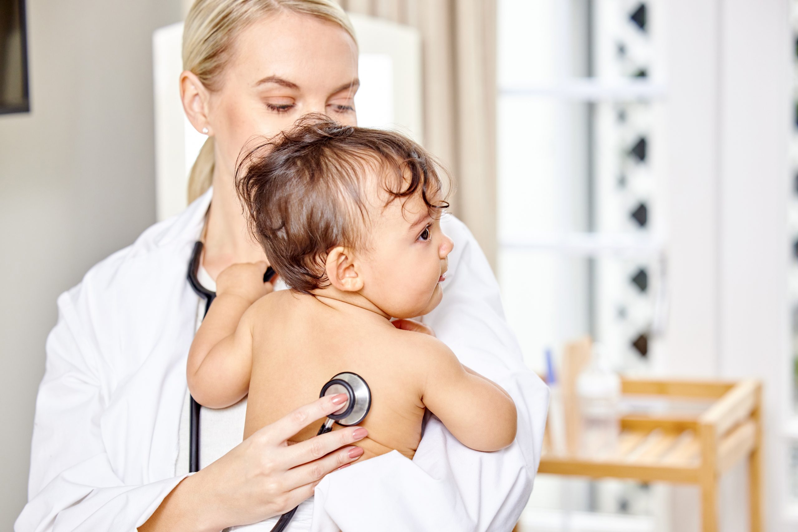 Baby mit Pseudokruppanfall auf dem Arm einer Ärztin