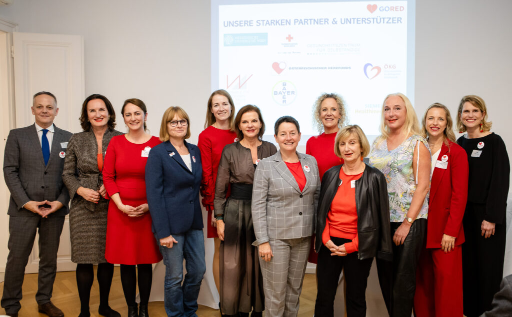 Bei der Kick-Off-Veranstaltung wurde ein Gruppenbild gemacht. Die Unterstützerinnen stehen vor einem Bildschirm auf dem alle Partnerorganisationen abgebildet sind.