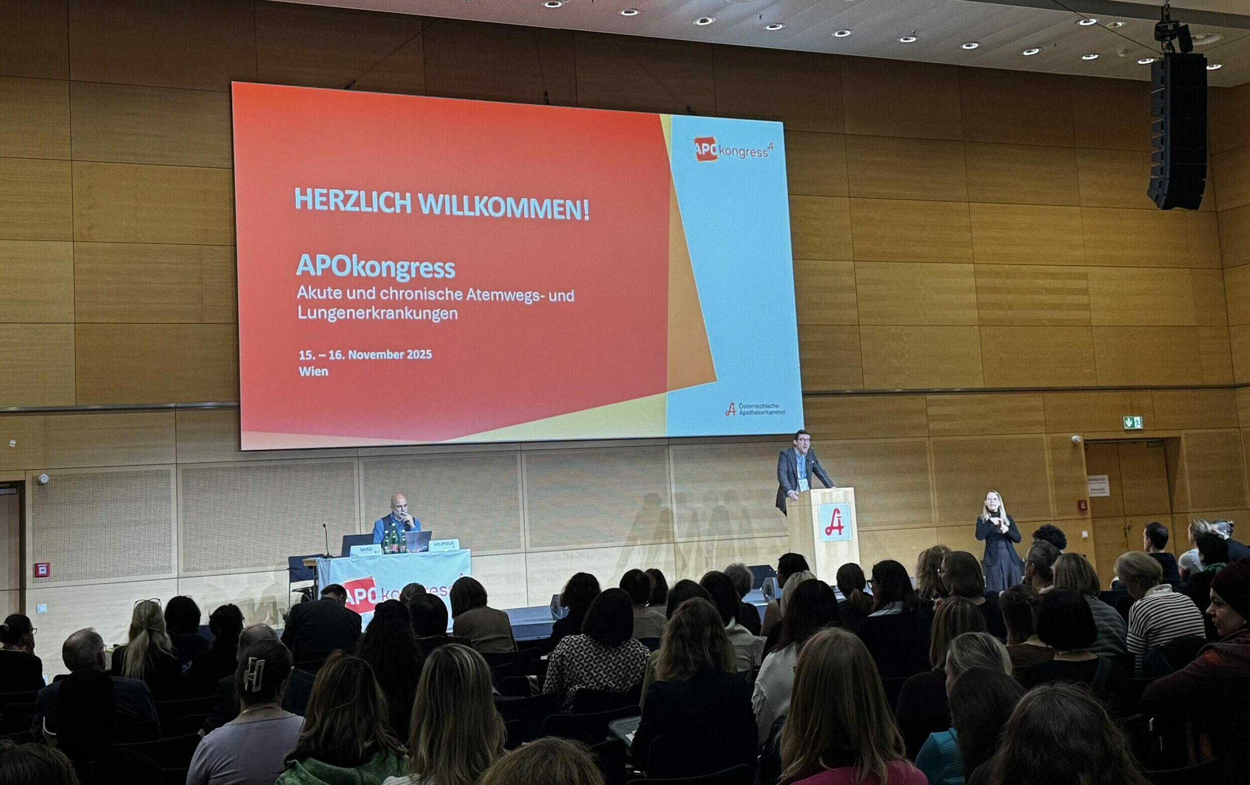Der Saal des Apokongress war bis auf den letzten Platz ausverkauft. Man sieht die Menge und Saiko am Rednerpult. Hinter ihm die Leinwand.