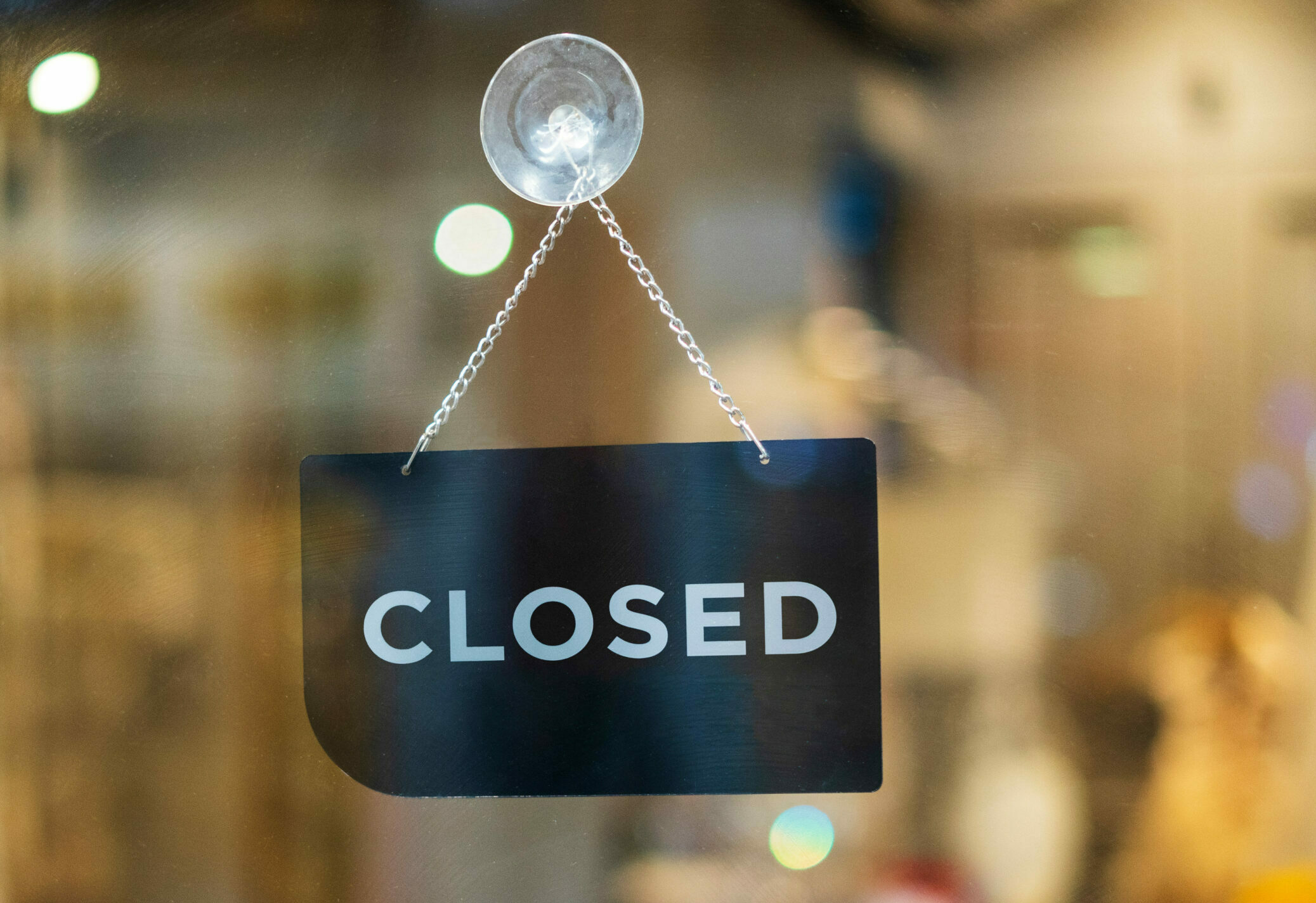 Symbolbild: Eine Glastür vor der rein Schild mit der Aufschrift "closed" hängt.