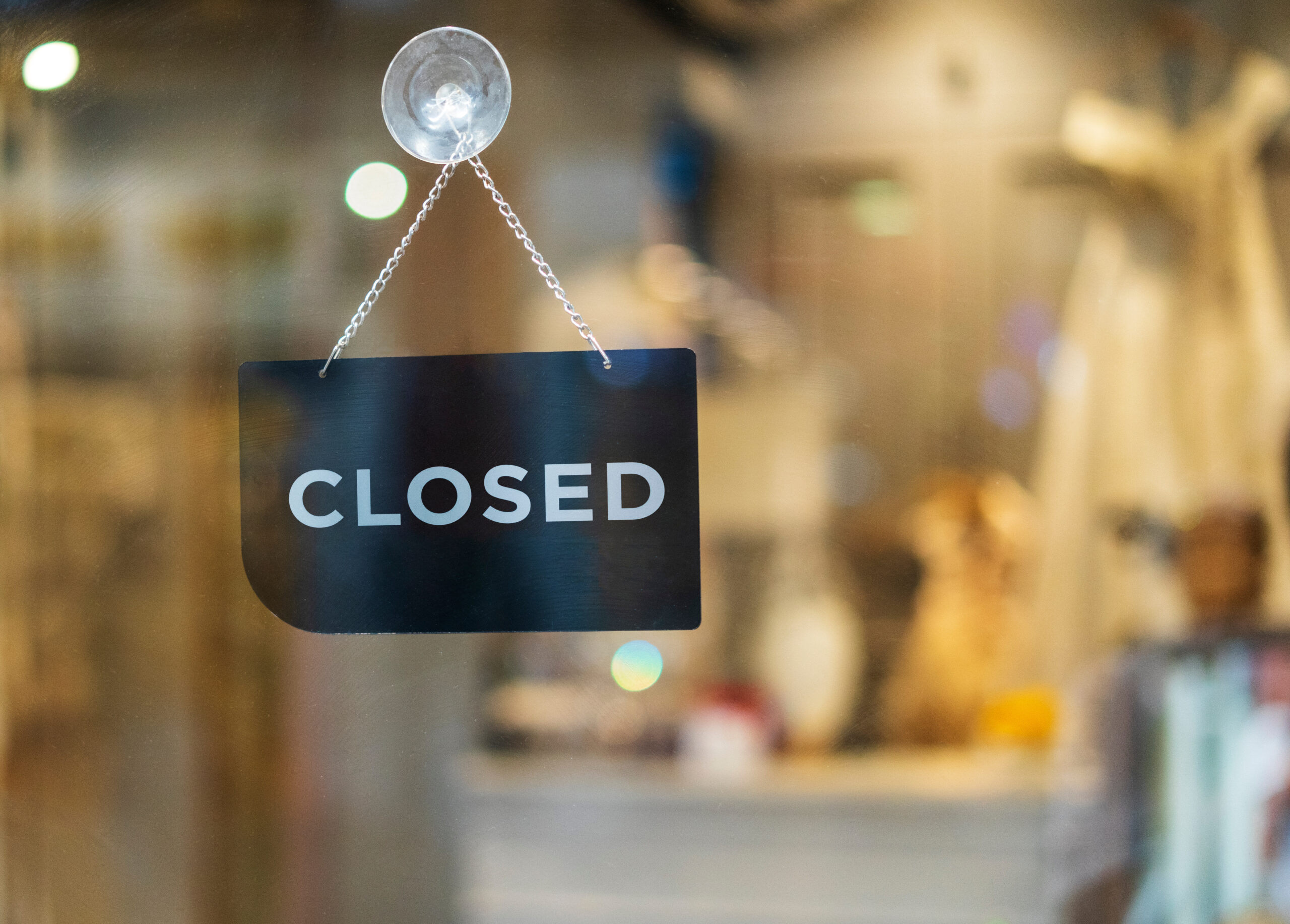 Symbolbild: Eine Glastür vor der rein Schild mit der Aufschrift "closed" hängt.