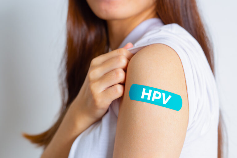 Symbolbild: IEn junges Mädchen zeigt ihren geimpften Arm. Auf ihm klebt ein Pflaster mit Aufschrift "HPV".