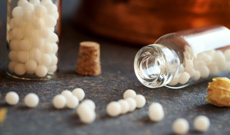 Symbolbild: Eine Glasphiole ist mit Globulin Kügelchen gefüllt. Sie liegt offen da.