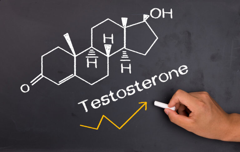 Symbolbild: Strukturformel von Testosteron mit Kreide gezeichnet von einer Hand. Darunter ein gelber Pfeil der ansteigt.