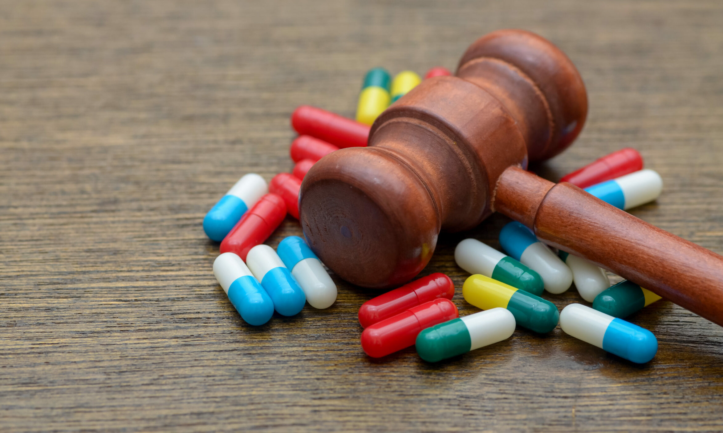 Symbolbild: Ein Richterhammer liegt in einer Menge voll bunter Kapseln.
