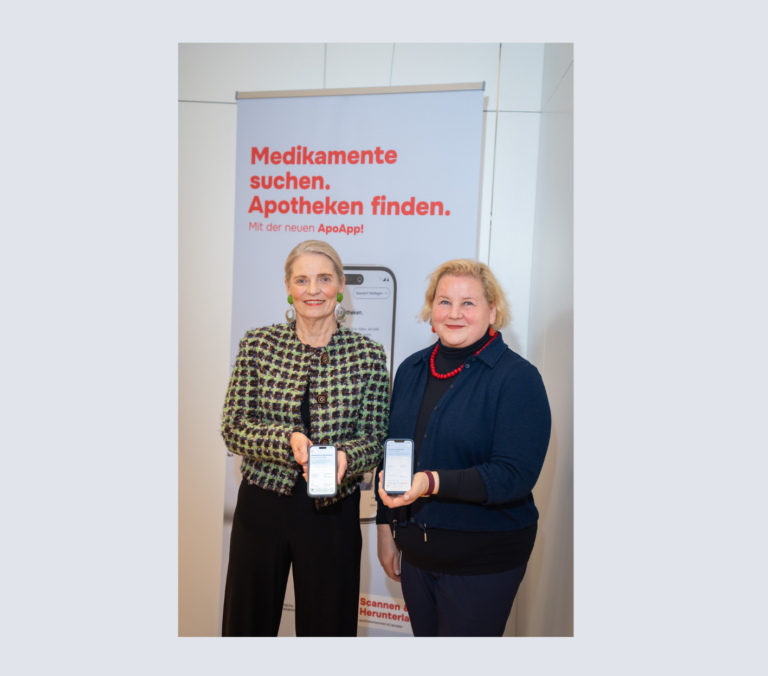 Gesundheitsministerin Korinna Schumann und Apothekerkammerpräsidentin Ulrike Mursch-Edlmayr präsentieren die neue ApoApp. Sie stehen vor einem Werbeplakat und halten ein Telefon mit der App in die Höhe.