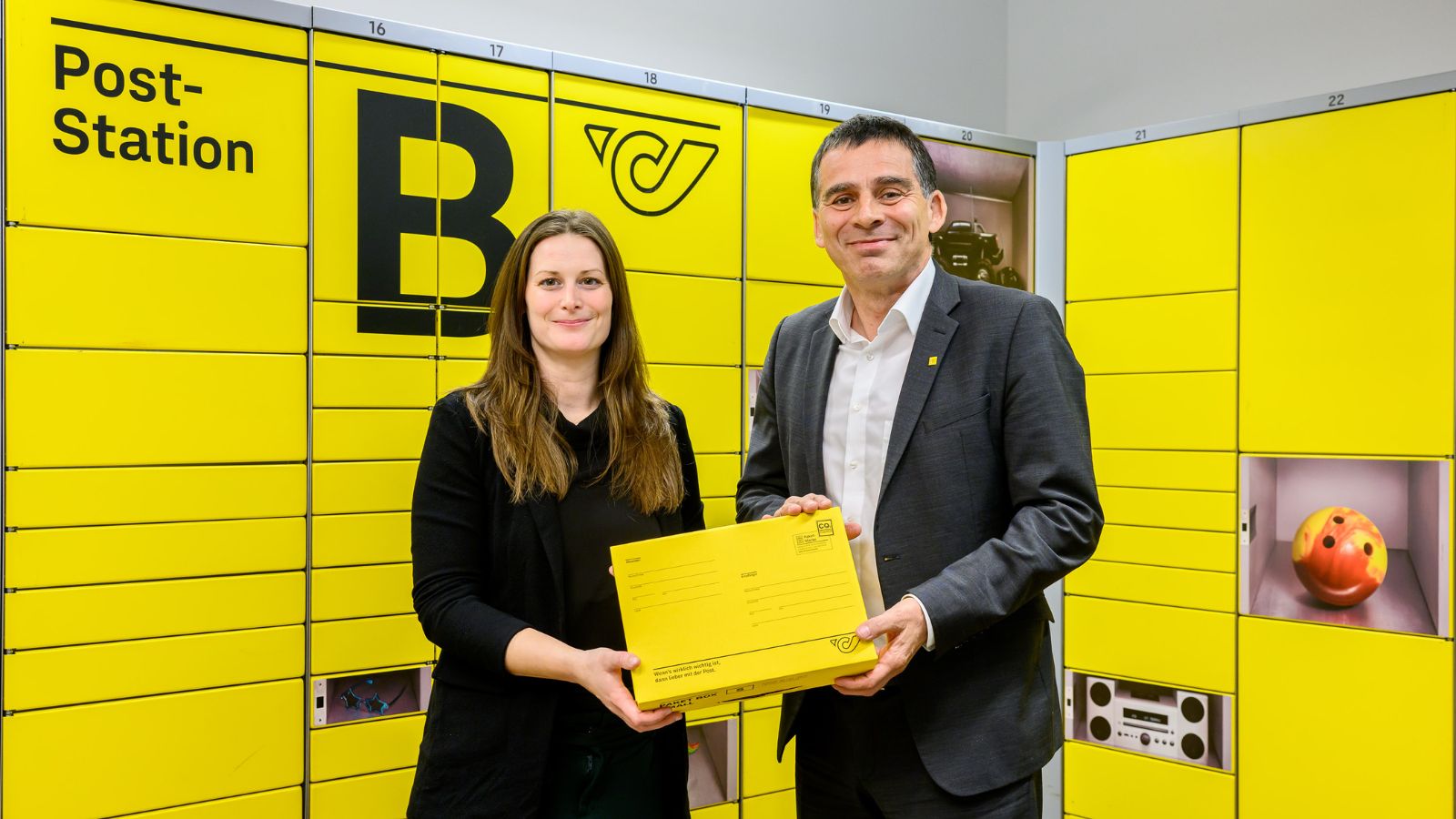 Martina Egger, Redcare, mit Peter Umundum, Österreichische Post, symbolisieren die neue Partnerschaft vor einer Poststation