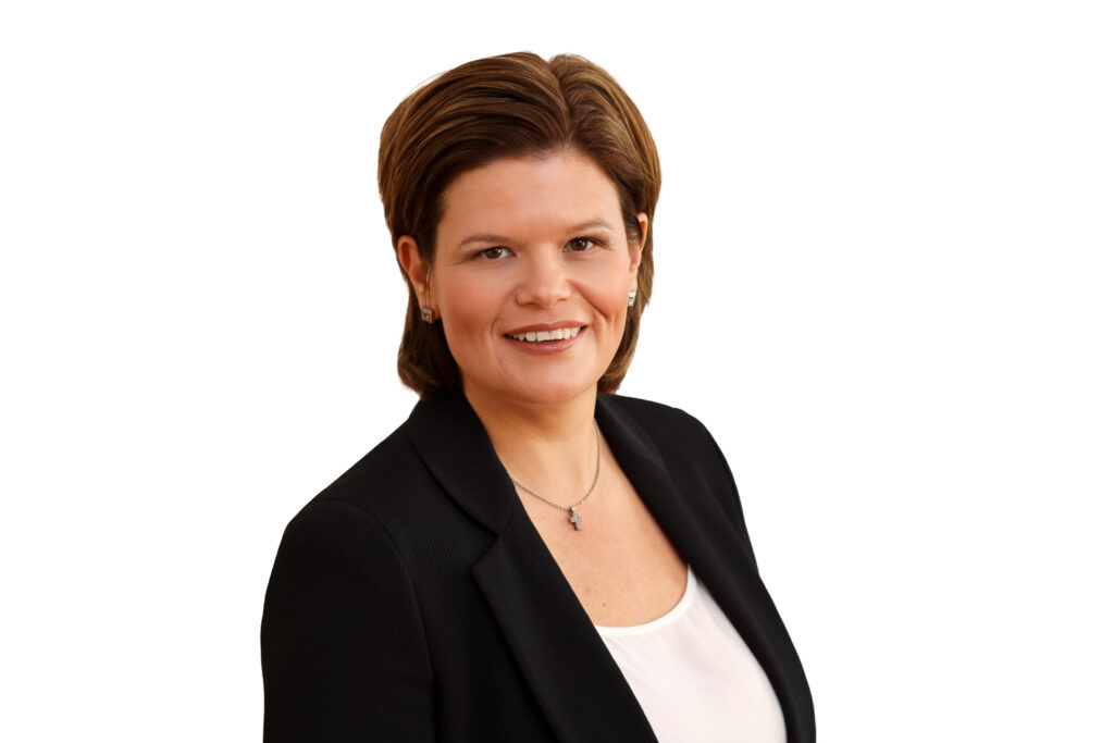 Christina Nageler trägt ein blaues Sakko und ein weißes Shirt. Sie lächelt in die Kamera. 