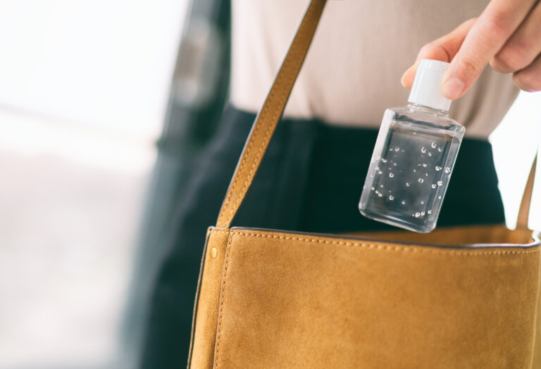 Symbolbild: Eine Frau gibt eine Handdesinfektionsmittel in ihre Handtasche.