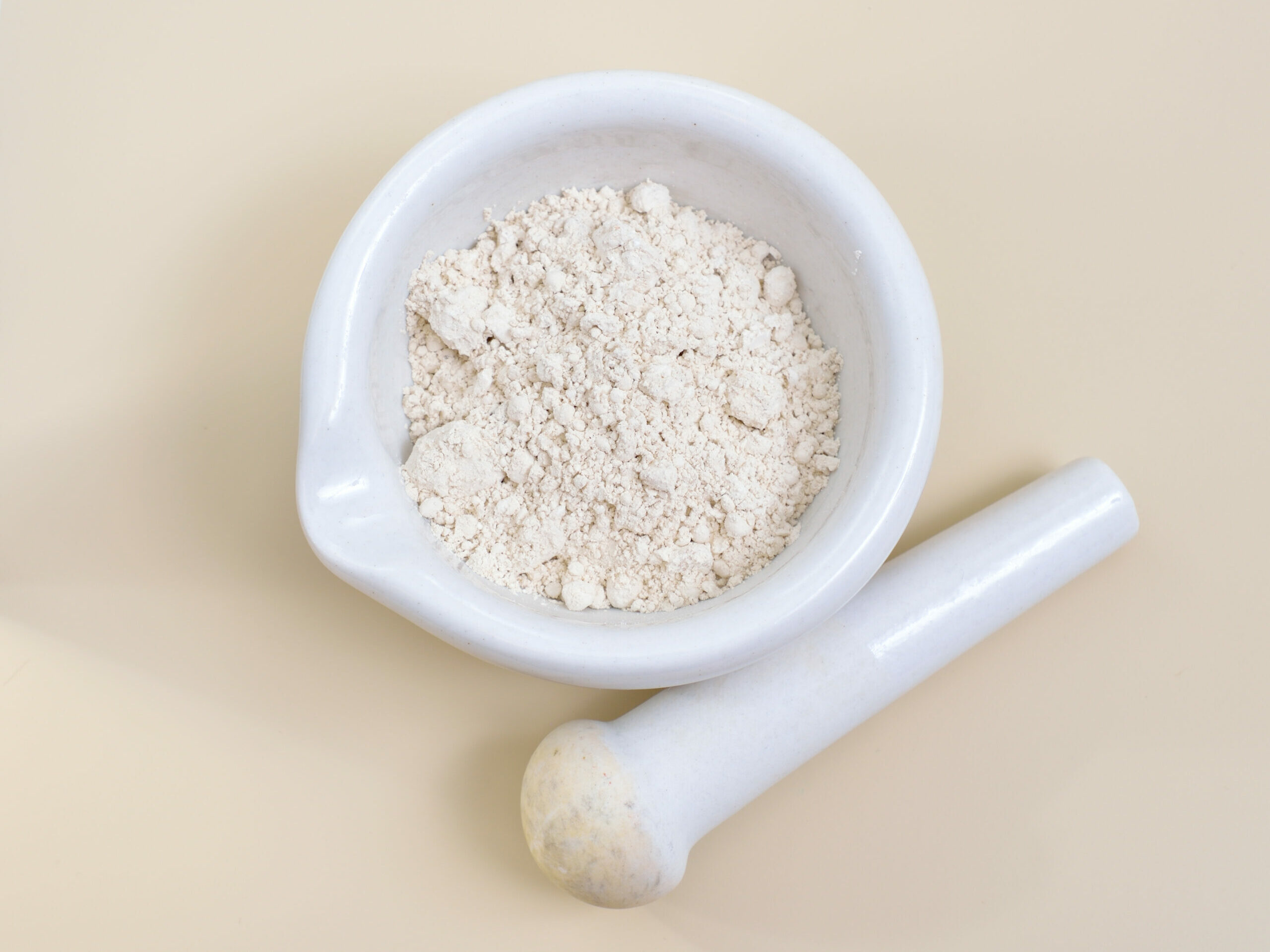 Symbolbild: Kieselerde in einer Reibschale mit Pistill daneben.