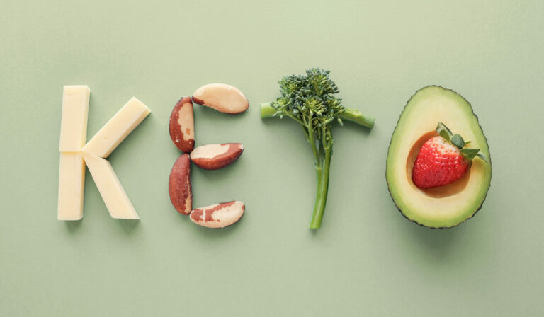 Das Wort "Keto" wird aus Käse, Brokkoli, Nüssen und einer Avocado mit Erdbeere geschrieben.