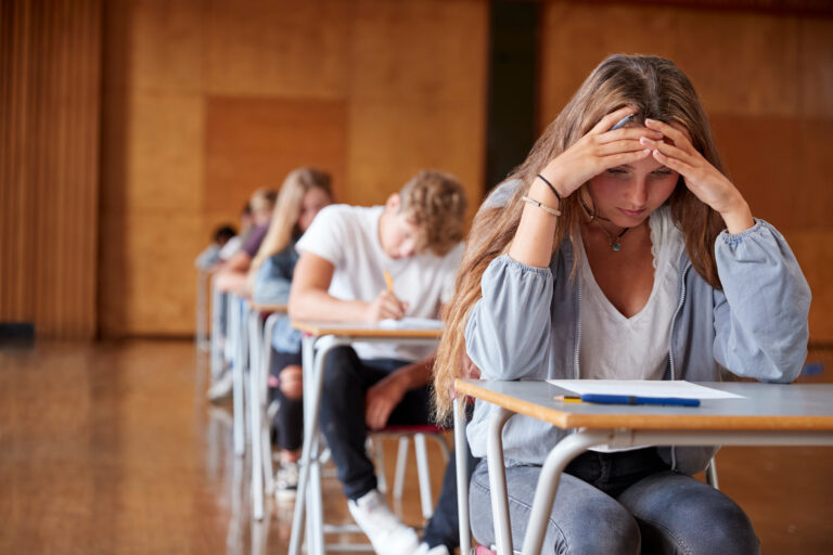 Symbolbild: Eine Prüfungssituation im Klassenzimmer, eine Schülerin wirkt angespannt.