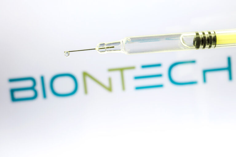 Symbolbild:Auf dem Bild ist das BioNTech-Logo zu sehen darüber eine Spritze mit gelblicher Flüssigkeit.