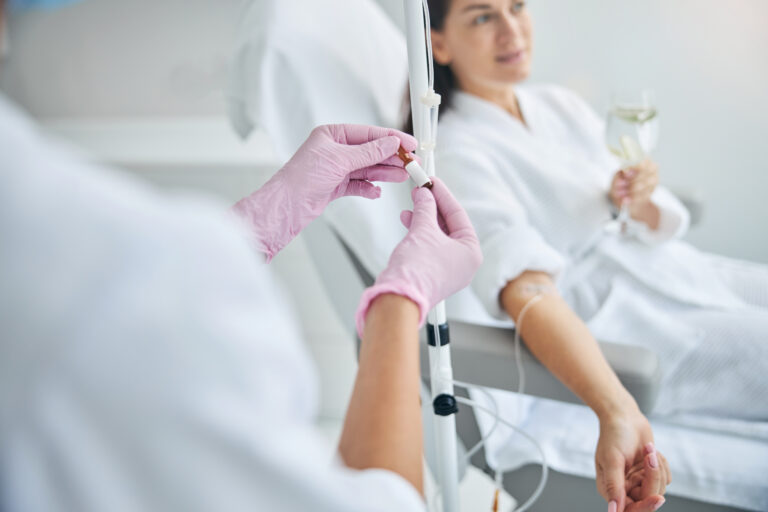Symbolbild: Eine Frau liegt auf einer Liege und bekommt eine Infusion.