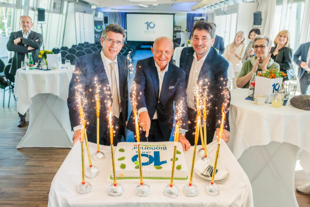 Drei Männer schneiden eine Torte an.