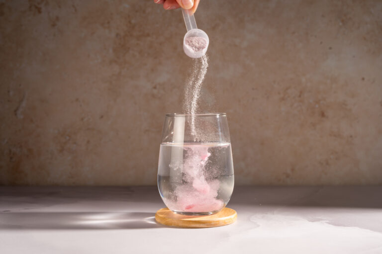 Symbolbild: Pulver wird aus einem Messlöffel in ein Glas mit Wasser geschüttet.