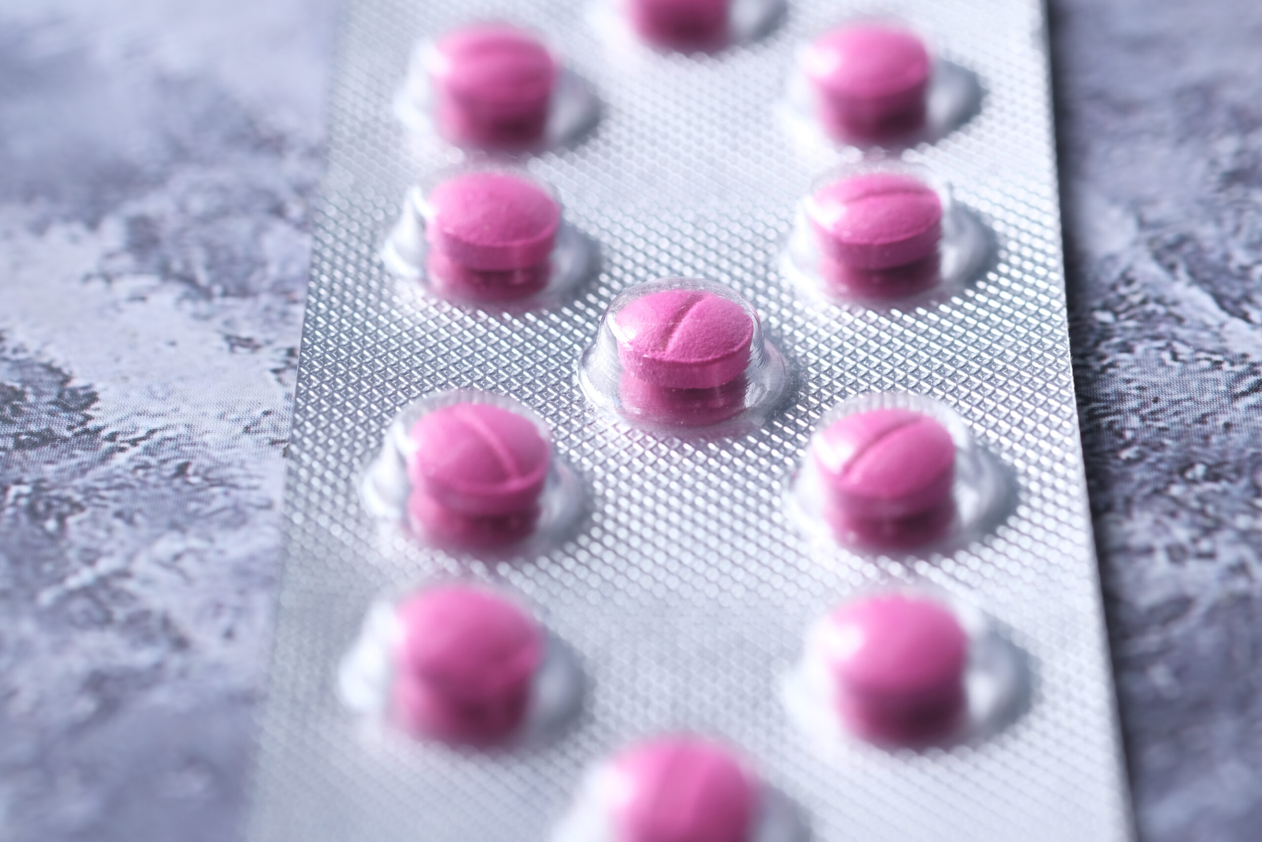 Symbolbild: Nahaufnahme von einem Tablettenblister gefüllt mit kleinen rosa Tabletten.