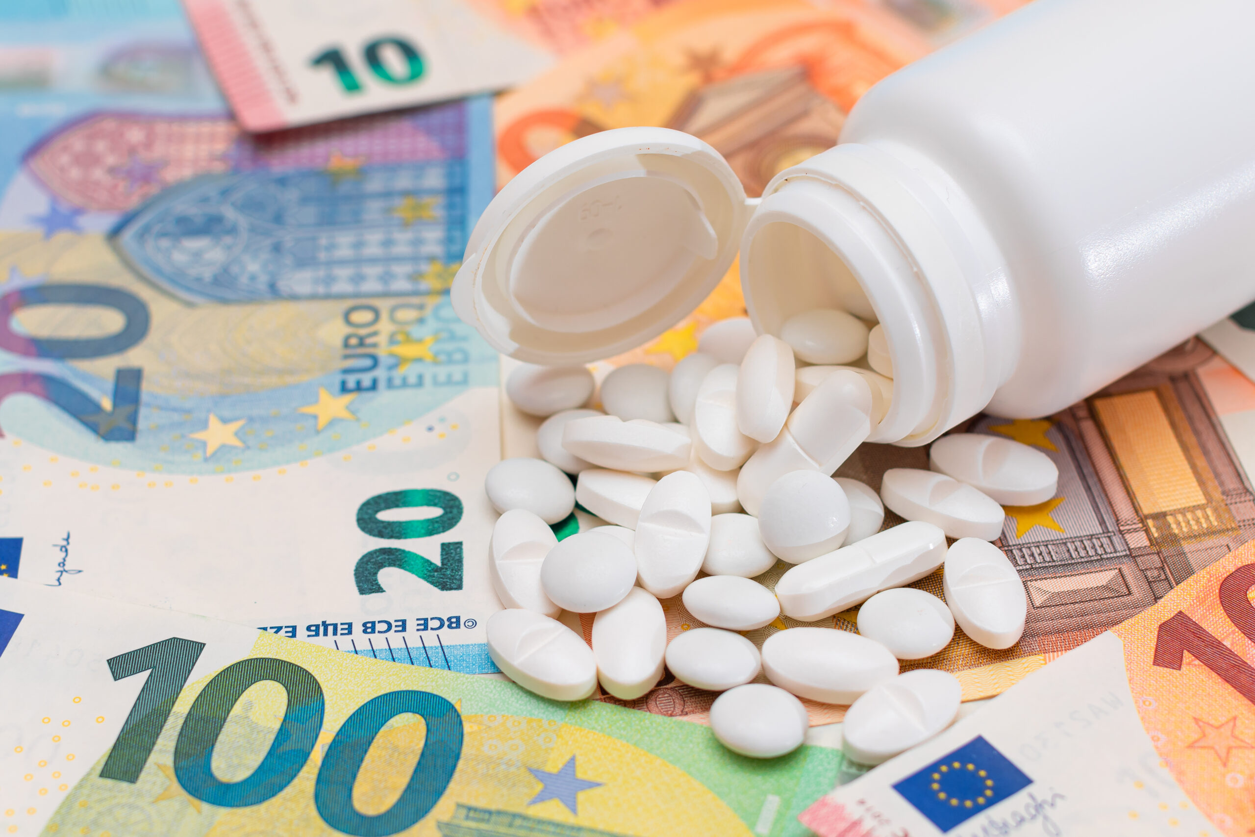 Symbolbild: Tabletten auf verschiedenen Euroscheinen.