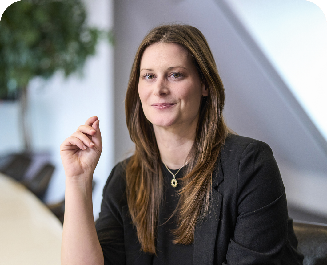 Martina Egger sitzt an einem Tisch. Sie trägt eine schwarze Bluse und lächelt.