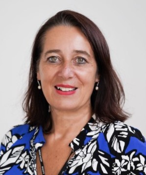 Christina Thaler trägt eine Blau-schwarze Bluse it weißen Blumen und lächelt.